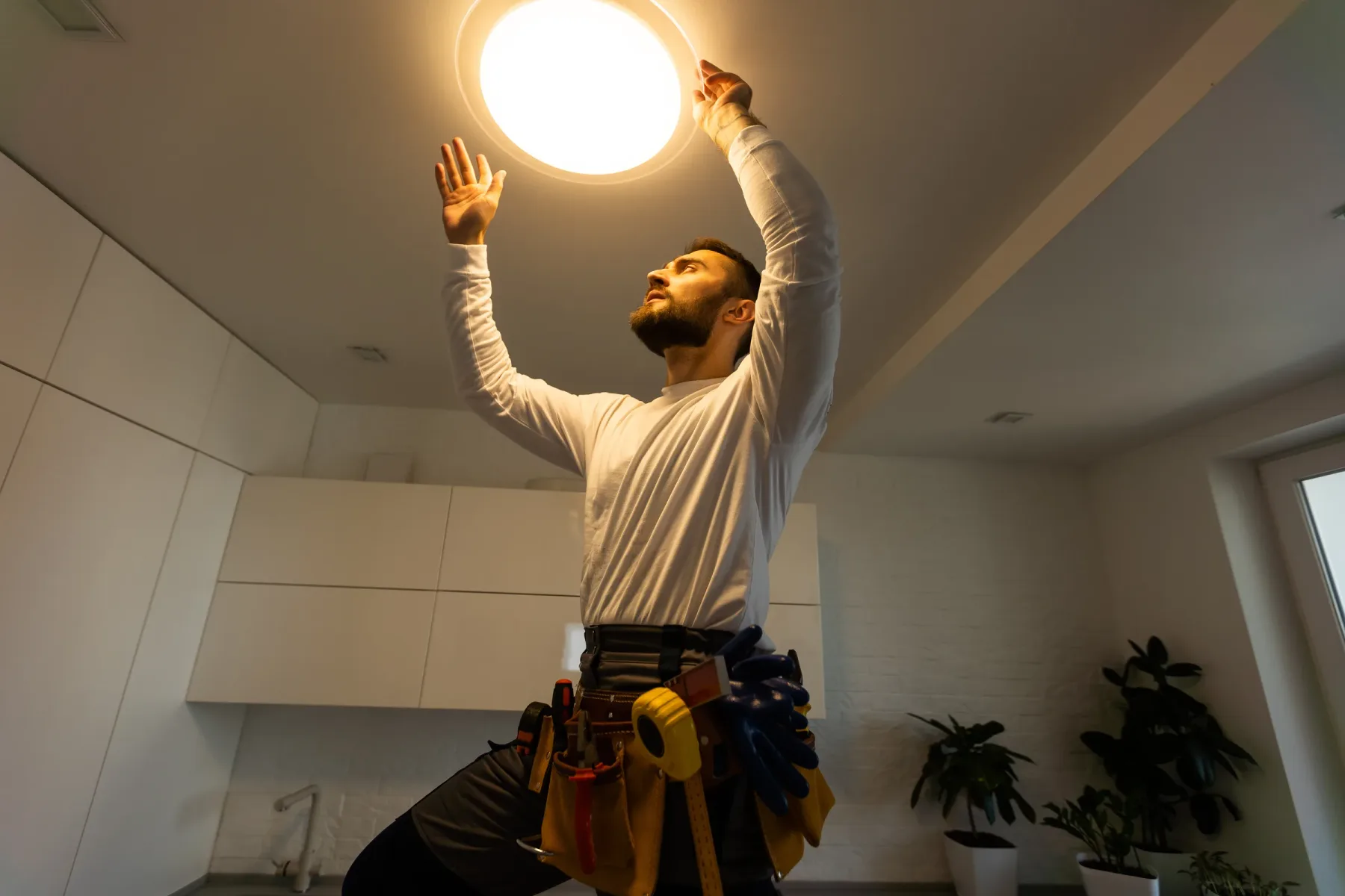 Electrician working on a ceiling light fixture.