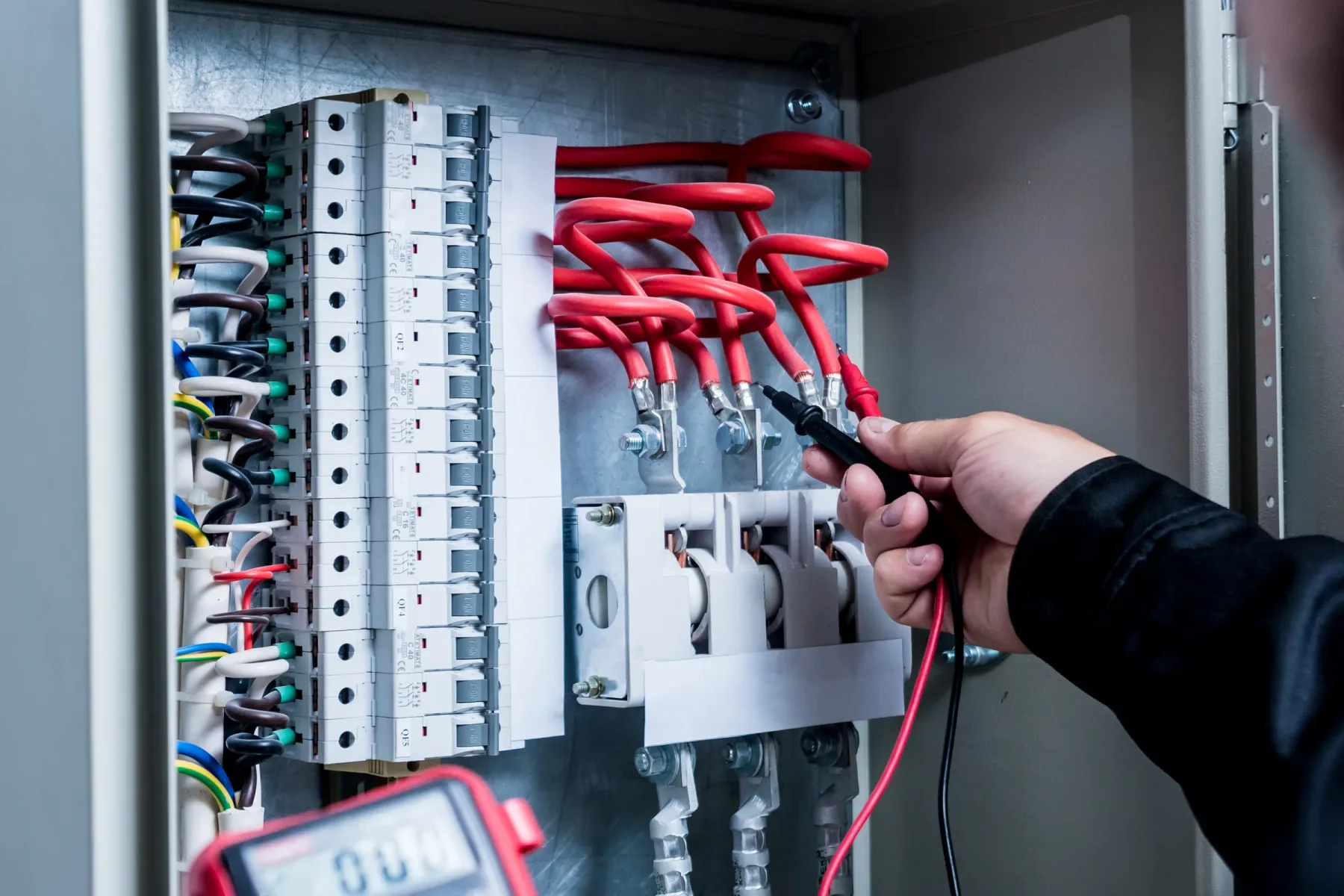 Electrician working on wiring inside an electrical panel.